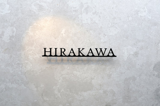 Custom metal sign displaying text in a sleek, modern font. Floating metal letters mounted on a light-colored textured background. Minimalist design suitable for home or business decor.