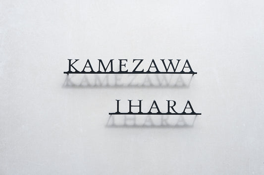 Custom metal sign displaying text in a sleek, modern font. Floating metal letters mounted on a light-colored textured background. Minimalist design suitable for home or business decor.