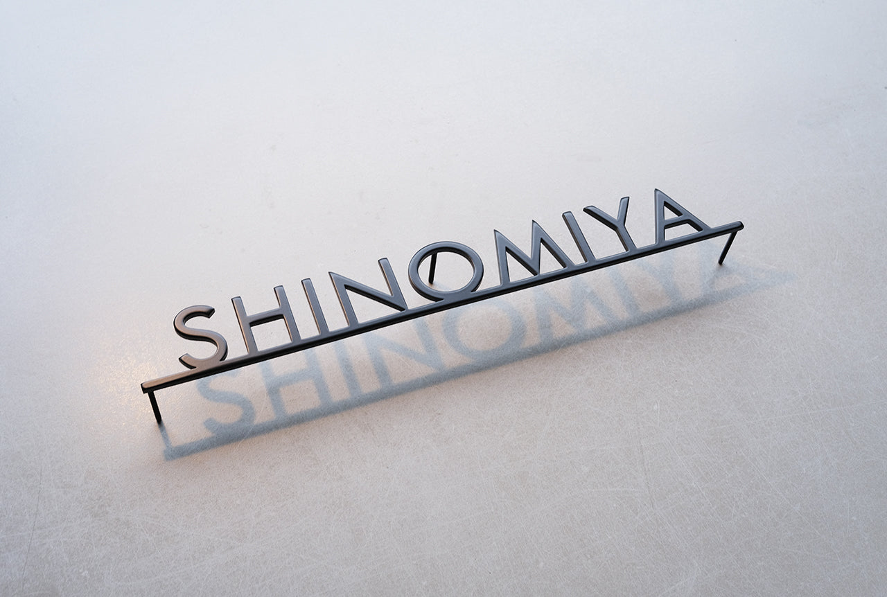Custom metal sign displaying text in a sleek, modern font. Floating metal letters mounted on a light-colored textured background. Minimalist design suitable for home or business decor.