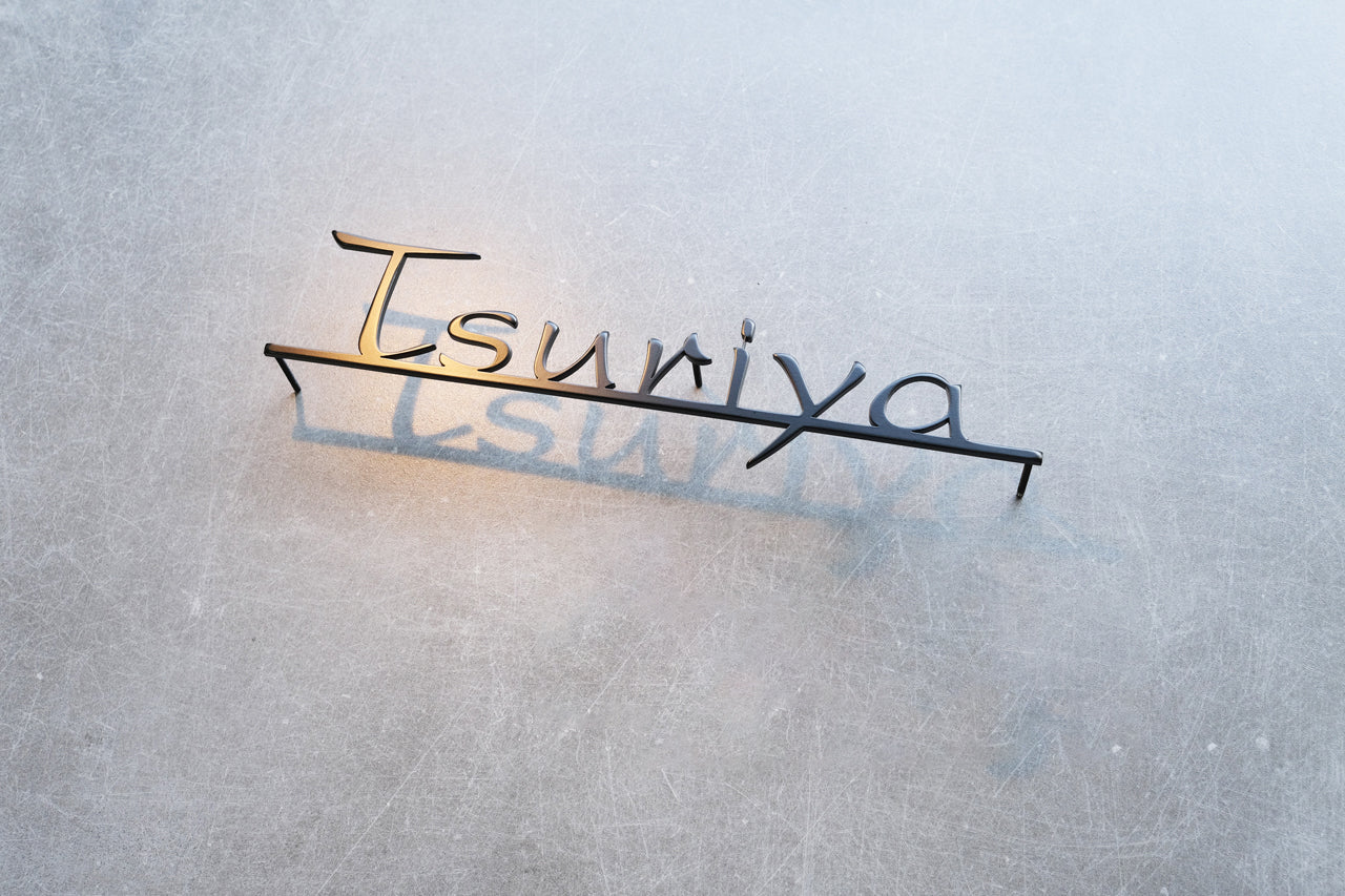 Custom metal sign displaying text in a sleek, modern font. Floating metal letters mounted on a light-colored textured background. Minimalist design suitable for home or business decor.