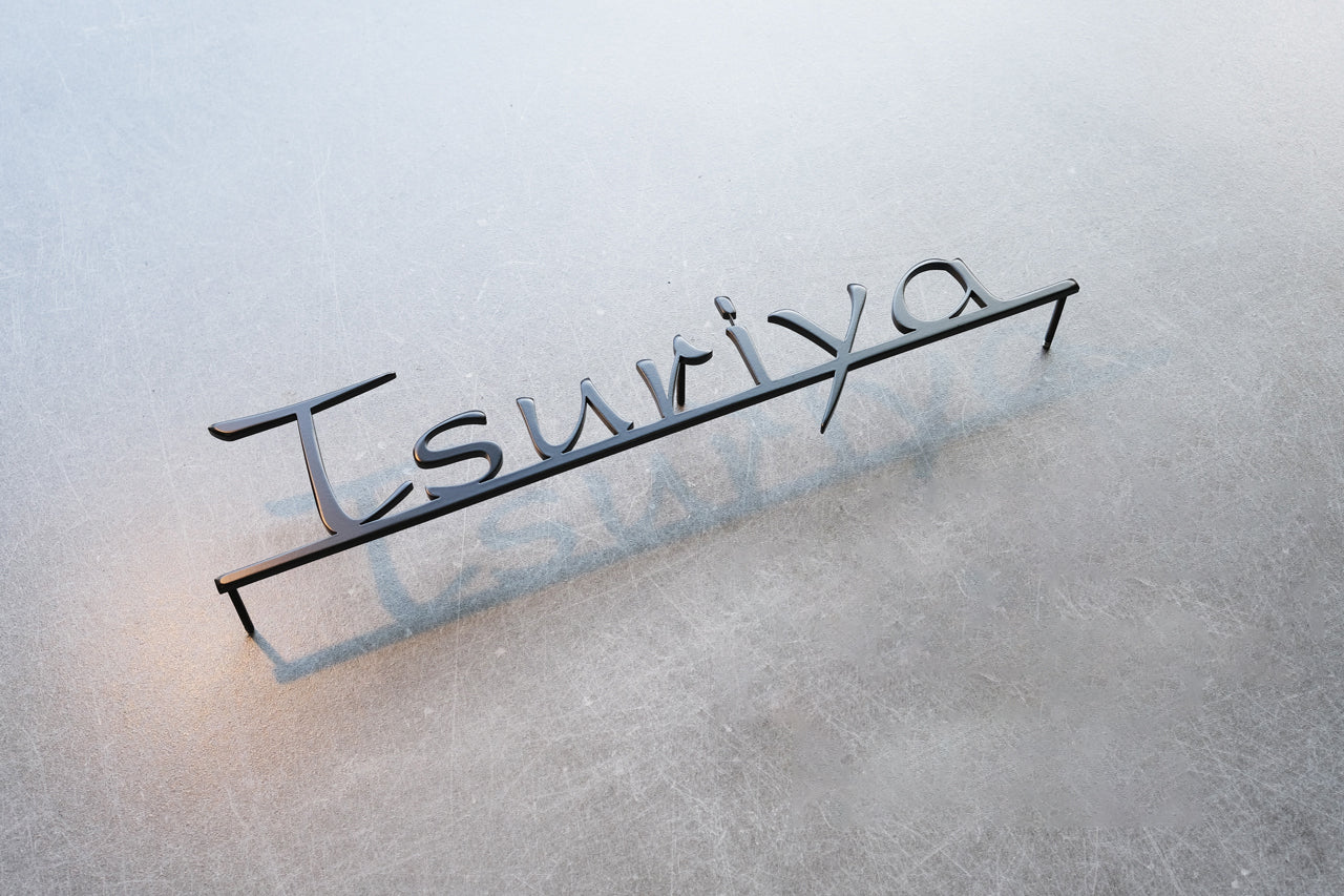 Custom metal sign displaying text in a sleek, modern font. Floating metal letters mounted on a light-colored textured background. Minimalist design suitable for home or business decor.