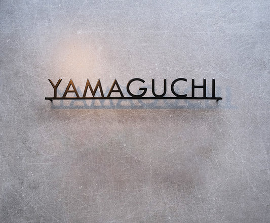 Custom metal sign displaying text in a sleek, modern font. Floating metal letters mounted on a light-colored textured background. Minimalist design suitable for home or business decor.