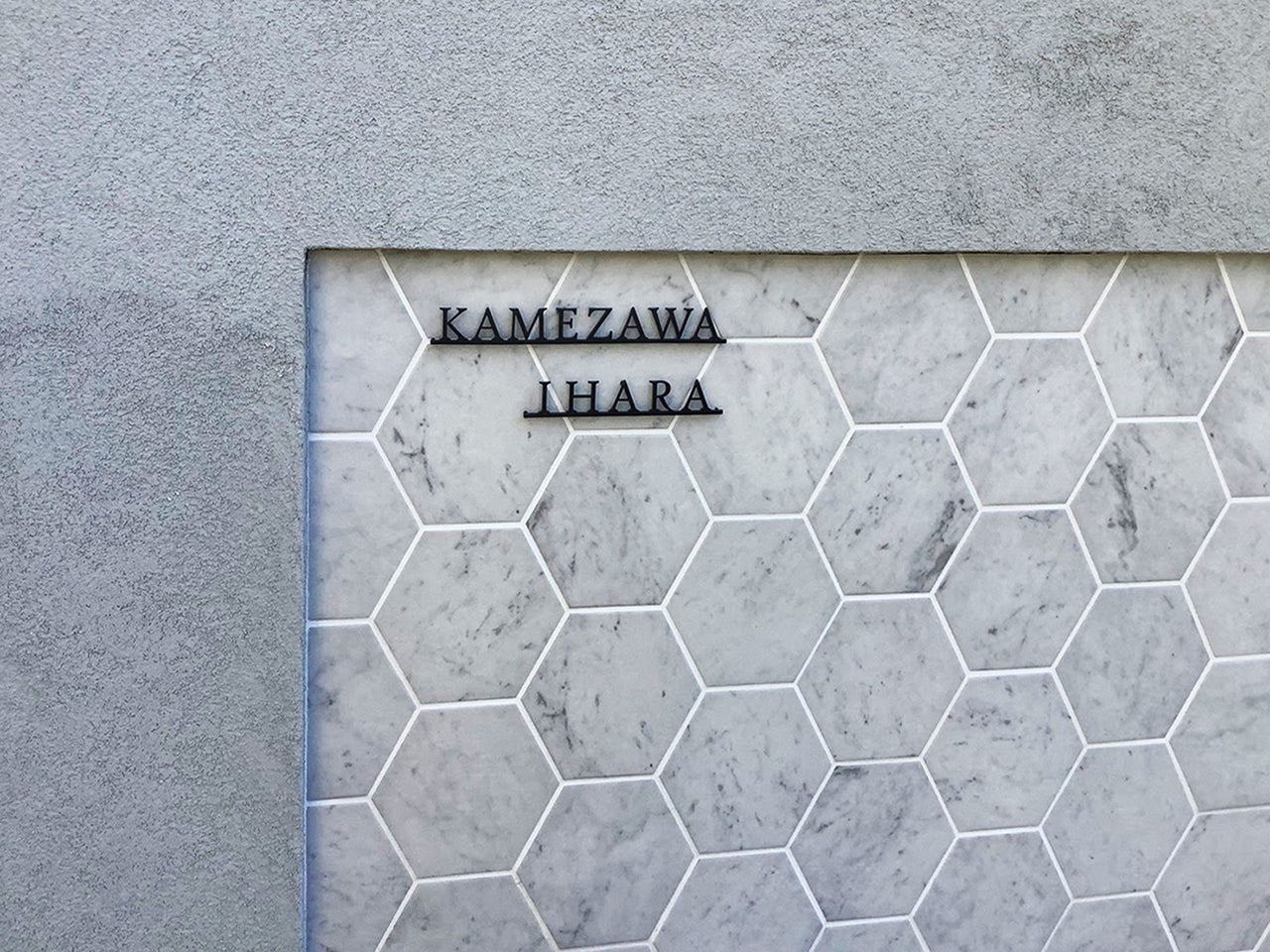 Custom metal sign displaying text in a sleek, modern font. Floating metal letters mounted on a light-colored textured background. Minimalist design suitable for home or business decor.