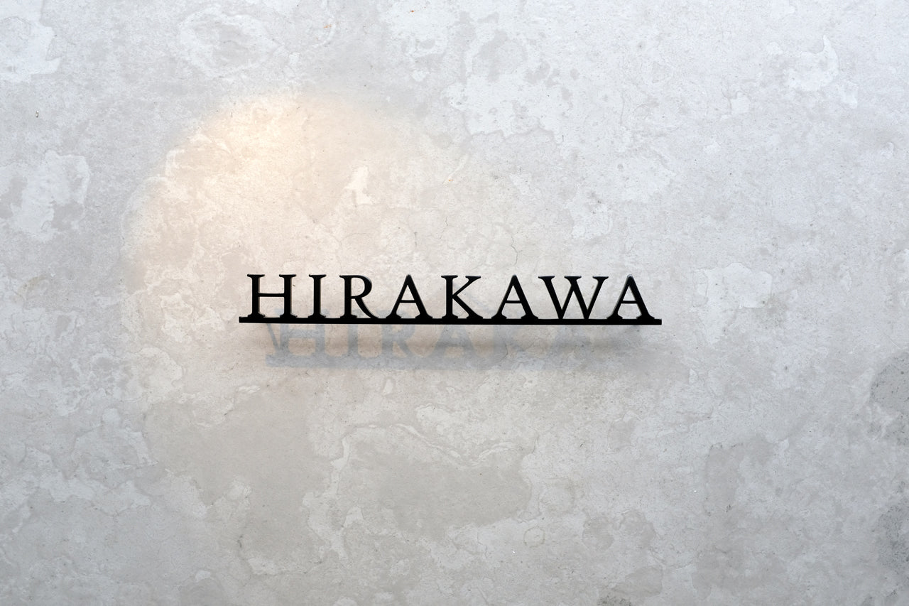 Custom metal sign displaying text in a sleek, modern font. Floating metal letters mounted on a light-colored textured background. Minimalist design suitable for home or business decor.