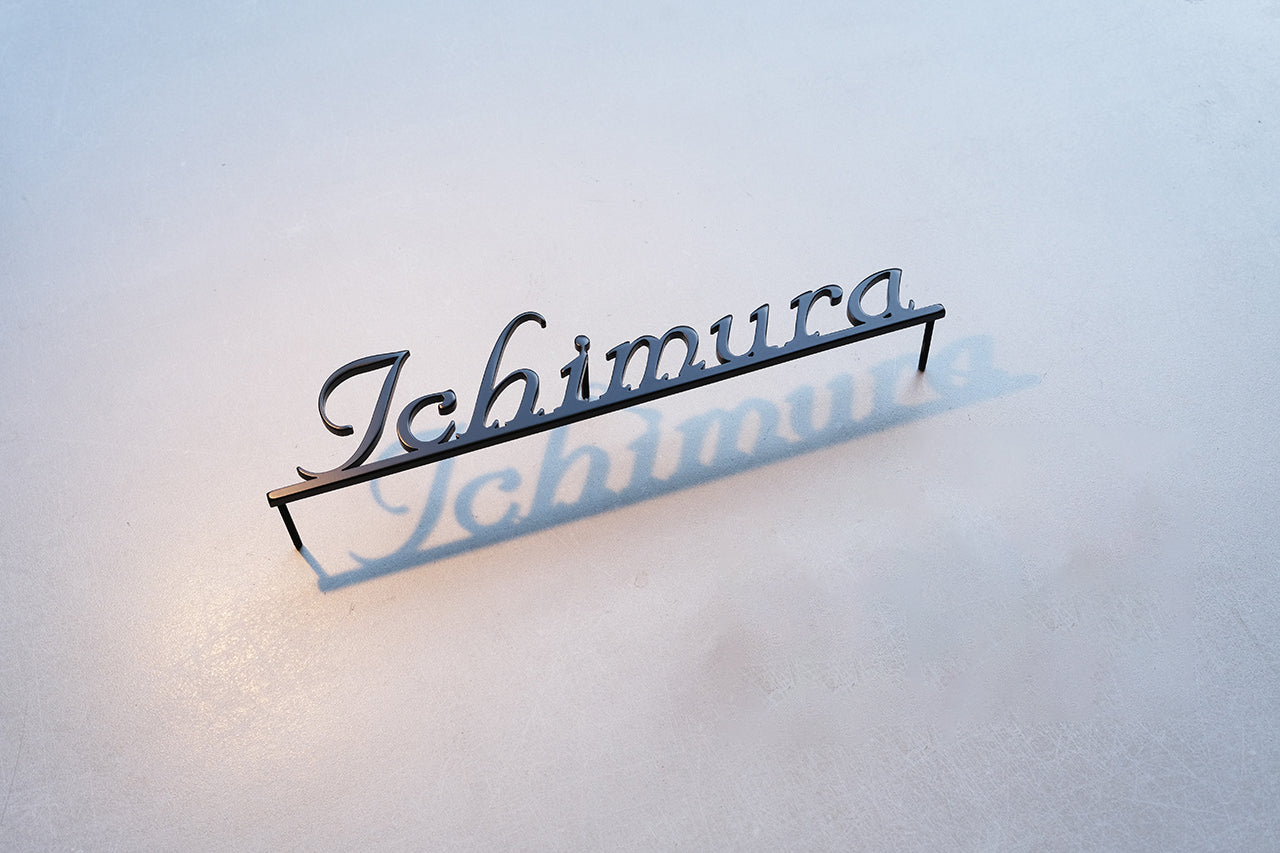 Custom metal sign displaying text in a sleek, modern font. Floating metal letters mounted on a light-colored textured background. Minimalist design suitable for home or business decor.