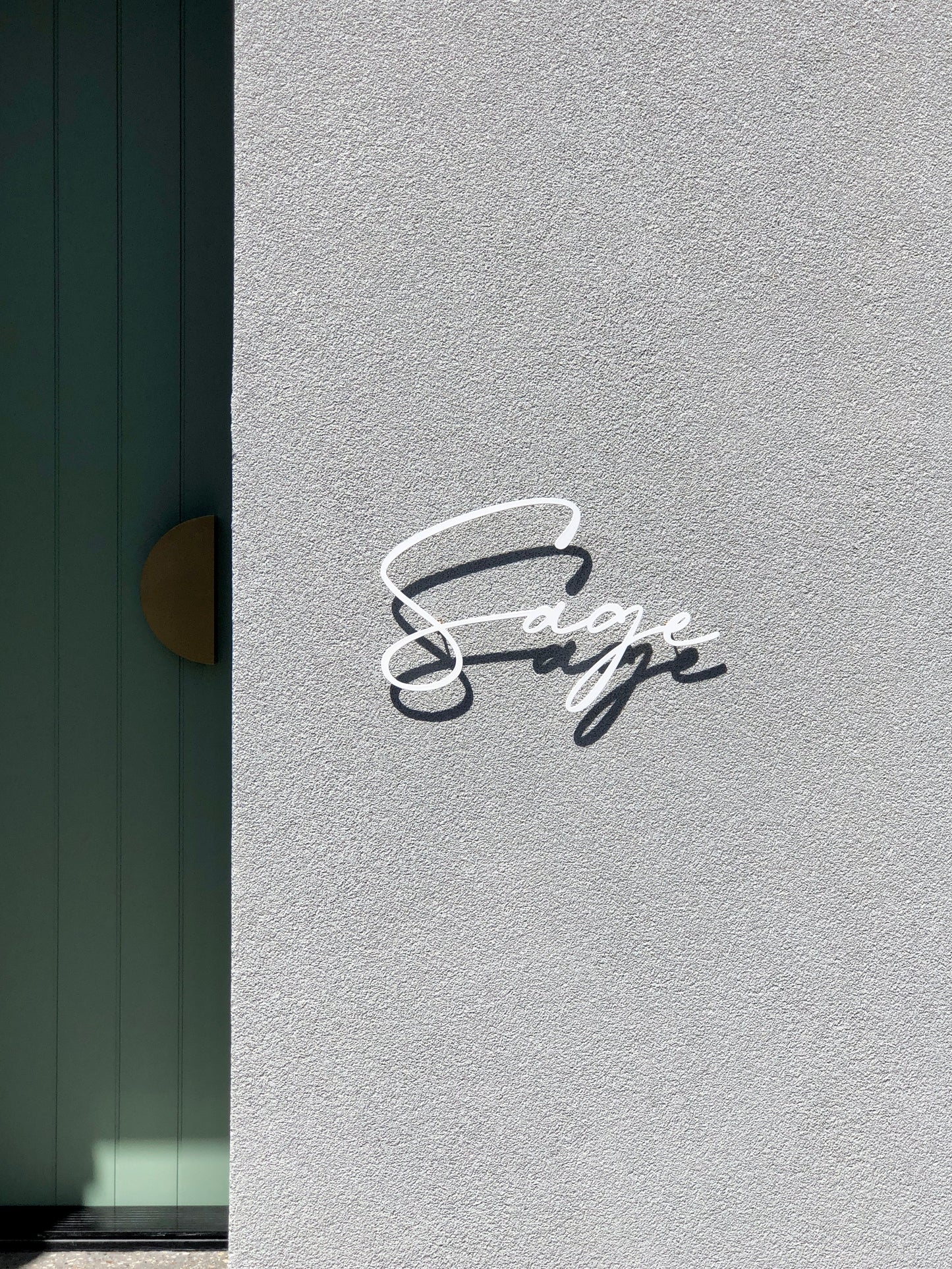 Custom metal sign displaying text in a sleek, modern font. Floating metal letters mounted on a light-colored textured background. Minimalist design suitable for home or business decor.