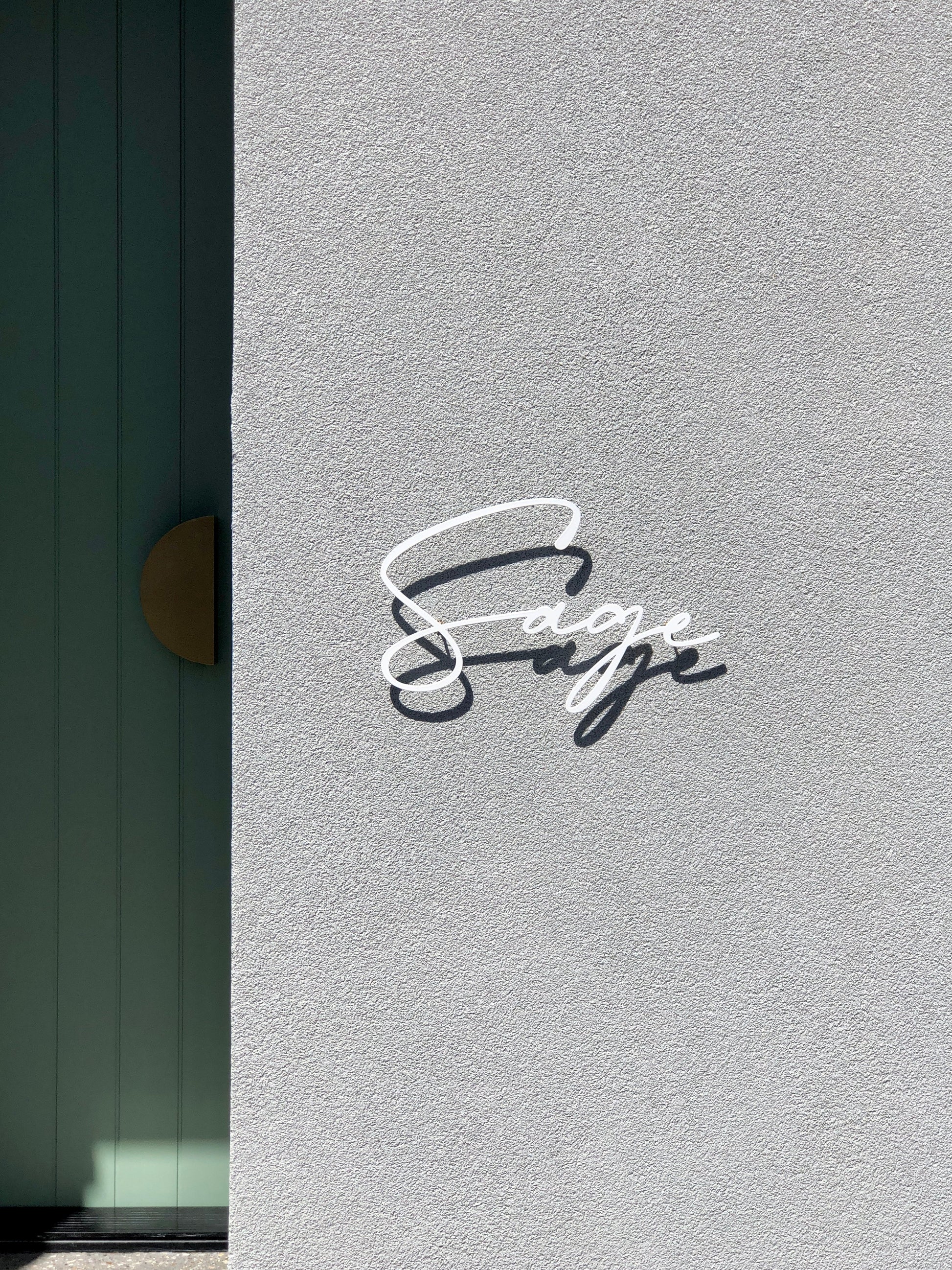 Custom metal sign displaying text in a sleek, modern font. Floating metal letters mounted on a light-colored textured background. Minimalist design suitable for home or business decor.