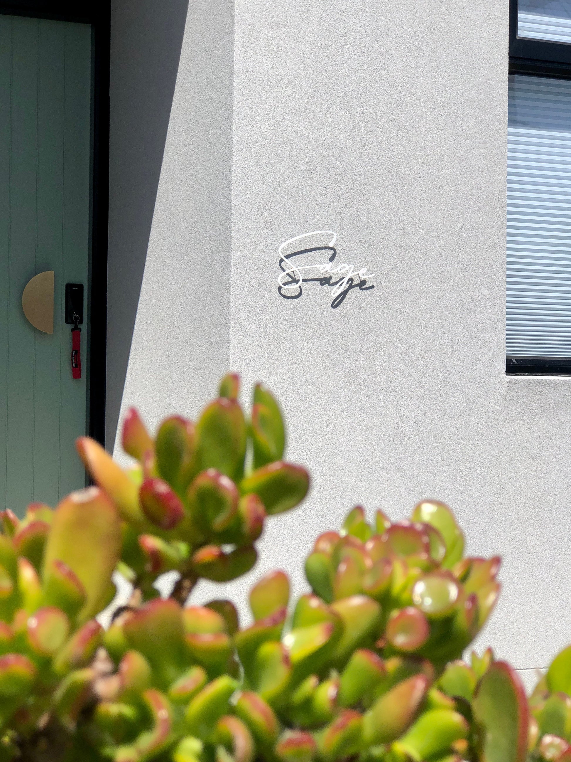 Custom metal sign displaying text in a sleek, modern font. Floating metal letters mounted on a light-colored textured background. Minimalist design suitable for home or business decor.